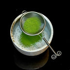 Grünes Pulver im feinen Sieb über Teeschale - Zubereitung