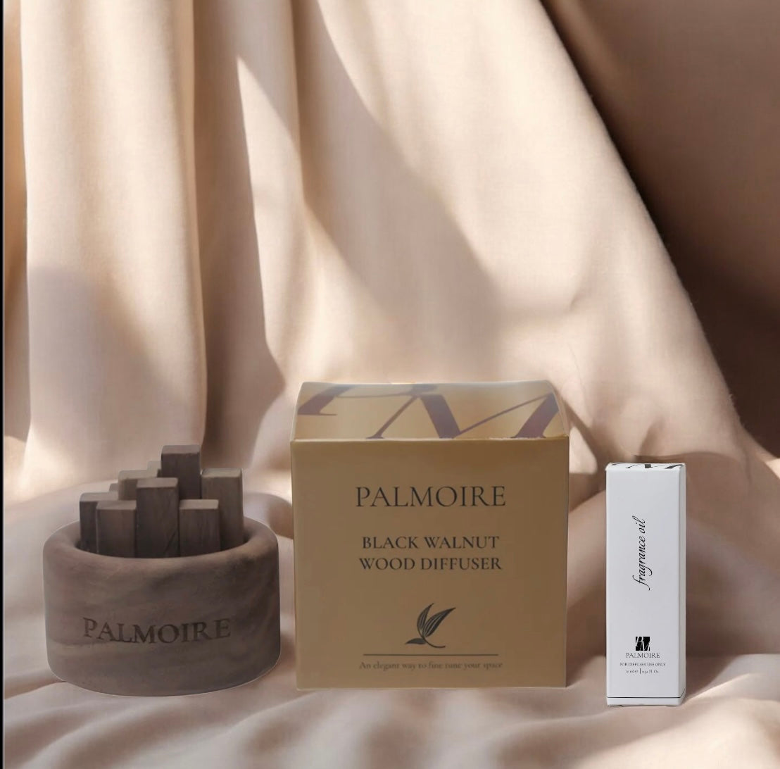 Ein Fitaura Mini Holzdiffusor aus Schwarznuss - Jasmin & Rose (To-Go), in einer beigen Schachtel, und eine weiße Schachtel mit ätherischem Öl werden auf einem weichen beigen Stoff präsentiert.